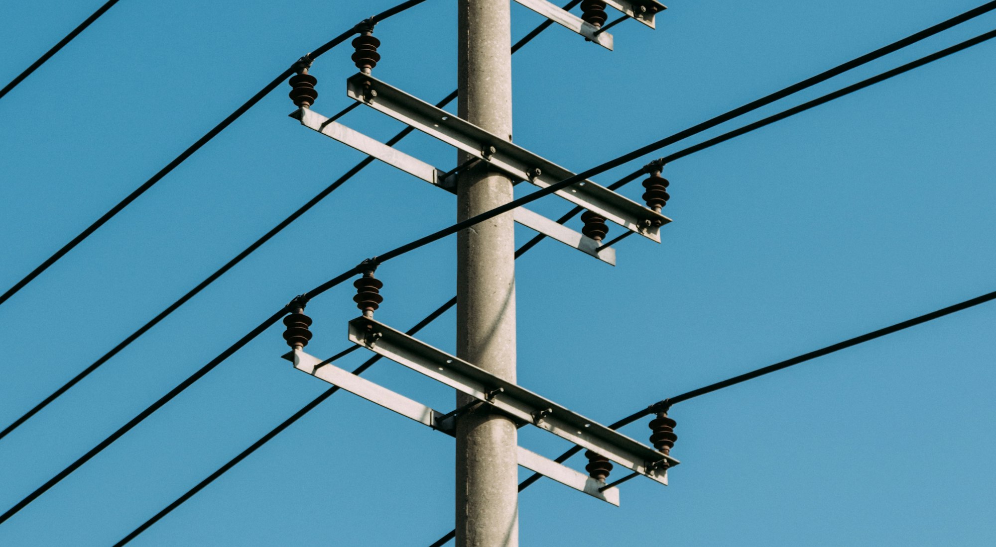 Telephone lines converging on a single pole against open sky